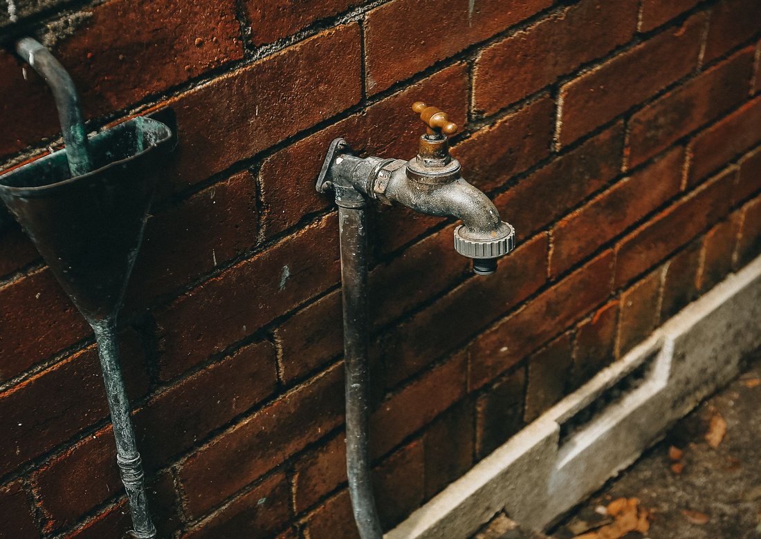 Licensed stock photograph: an outside faucet on the brick wall of a house.